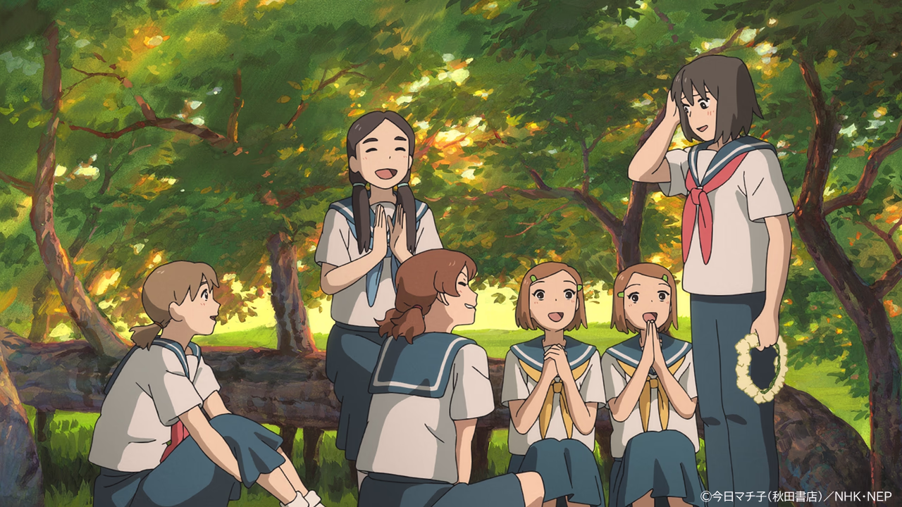 San stands holding a flower wreath as smiling classmates sit together under sunlit trees.