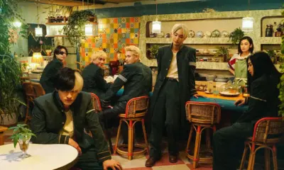 Six students in green uniforms lounge in a retro tiled cafe as a waitress watches