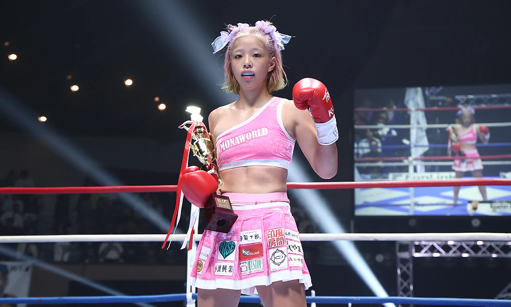 Mona Kimura alone in the ring with the trophy, glove raised to the camera, at K-1 WORLD MAX 2026.