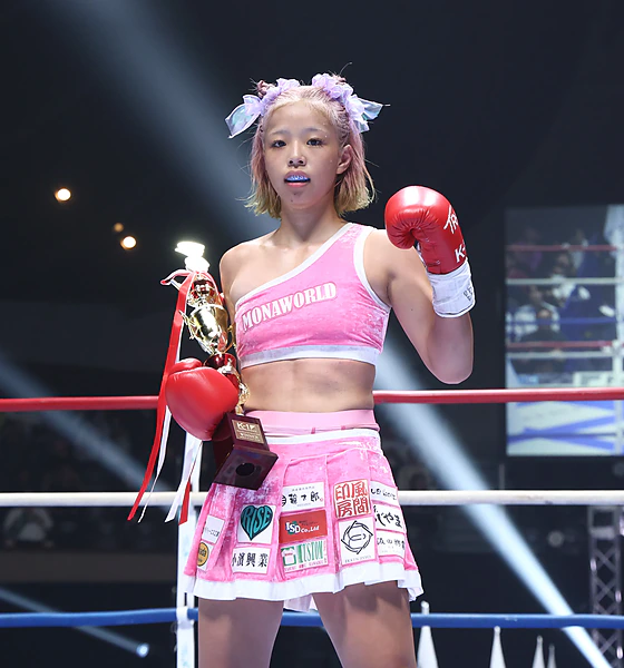 Mona Kimura alone in the ring with the trophy, glove raised to the camera, at K-1 WORLD MAX 2026.